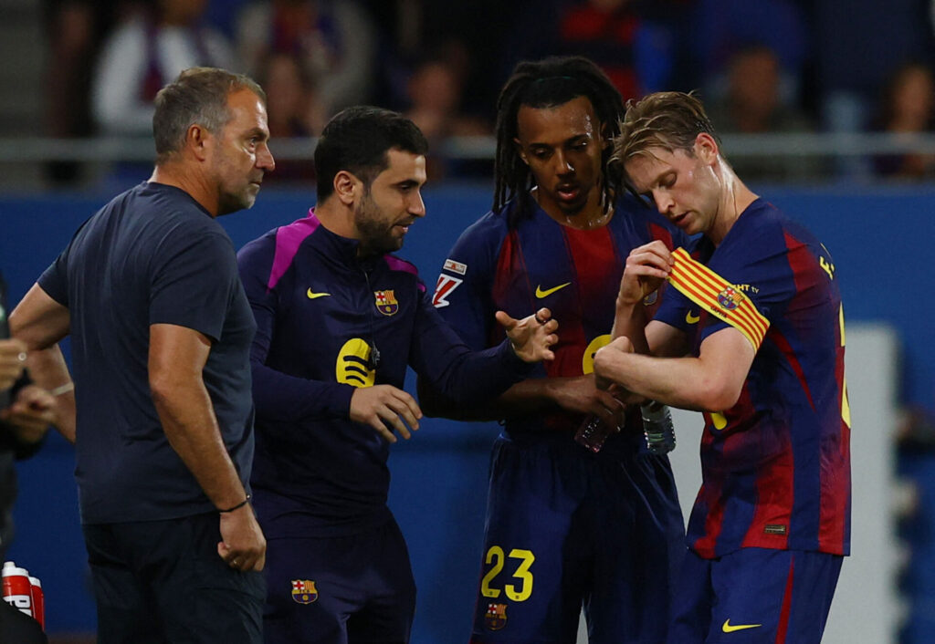 Frenkie de Jong får anførerbindet på, mens han og Jules Koundé får instruktioner af Hansi Flick.