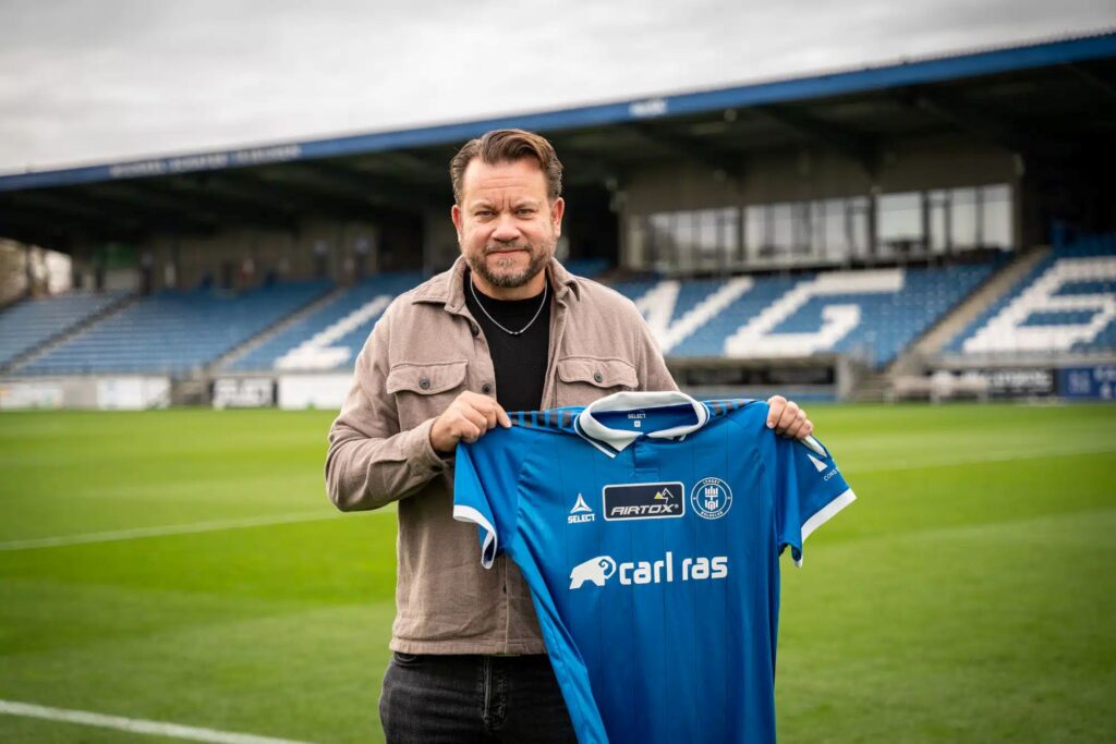 Jack Majgaard står på Lyngby Stadion, hvor han holder en Lyngby-trøje op.
