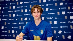 August Priske sidder iklædt en Birmingham-trøje med en kuglepen i hånden.