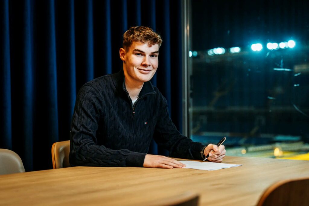 Mathias 'P' Jensen skriver under på en kontrakt med Brøndby Stadion i baggrunden.