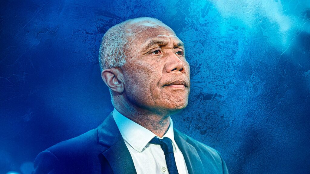 Antoine Kombouaré med blå baggrund.