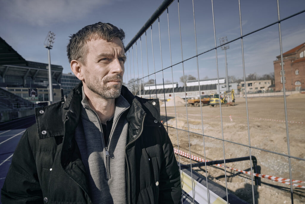 B.93's direktør, Christian Engell, foran et hegn poå et renoveret Østerbro Stadion