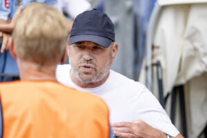 Carsten V. Jensen kigger på en mand i overtrækstrøje, mens han selv har en sort kasket på.