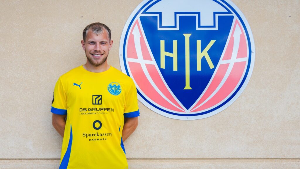 Runar Hauge med hænderne bag ryggen og Hobro-logo i baggrunden.