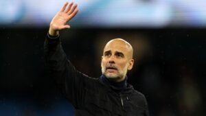 Pep Guardiola står med højre arm oppe i luften.