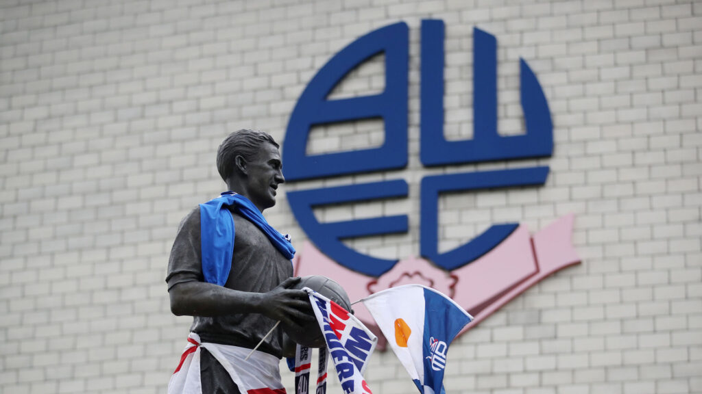 Bolton-logo med statue i forgrunden.
