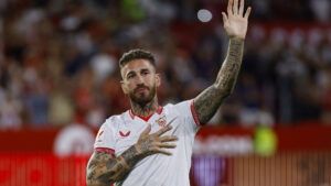 Sergio Ramos med én hånd i vejret den anden på Sevilla-logoet.