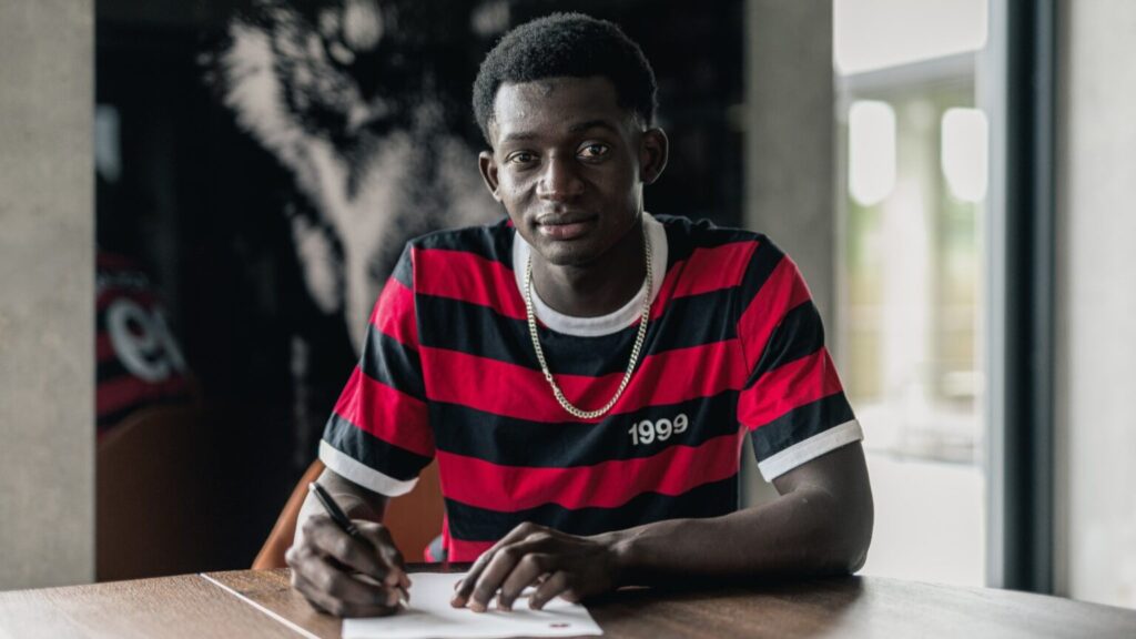 Abdou Aziz Ndiaye skriver under på et stykke papir.