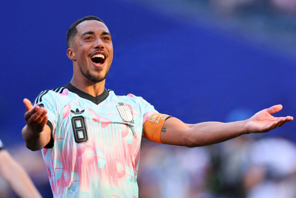 Youri Tielemans slår ud med armene og smiler.