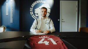 Diant Ramaj med en kuglepen i hånden og en FCK-trøje foran sig.